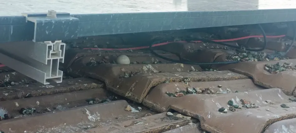 Interior del vehículo desordenado con cableado, aislamiento marrón roto y escombros debajo de un marco de metal.