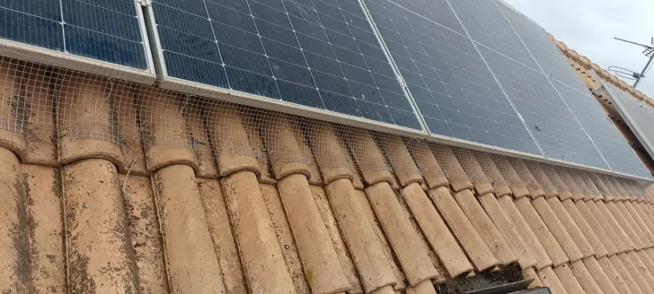 Paneles solares instalados en un tejado de tejas bajo un cielo azul.