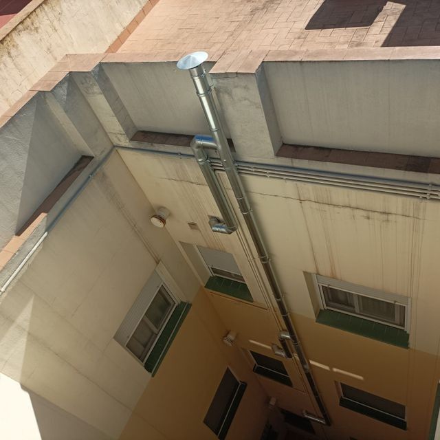 Una larga chimenea metálica se extiende hacia arriba a través del patio del edificio.