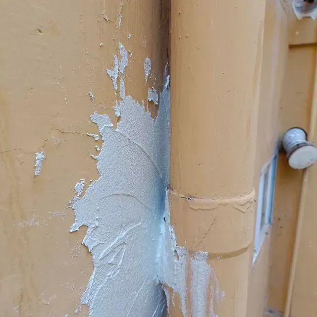 Pared beige y tubería amarilla selladas con sellador blanco.