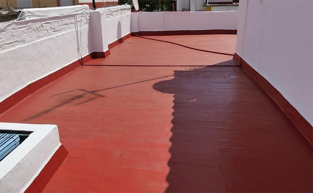 Azotea plana impermeabilizada de color rojo con paredes blancas.