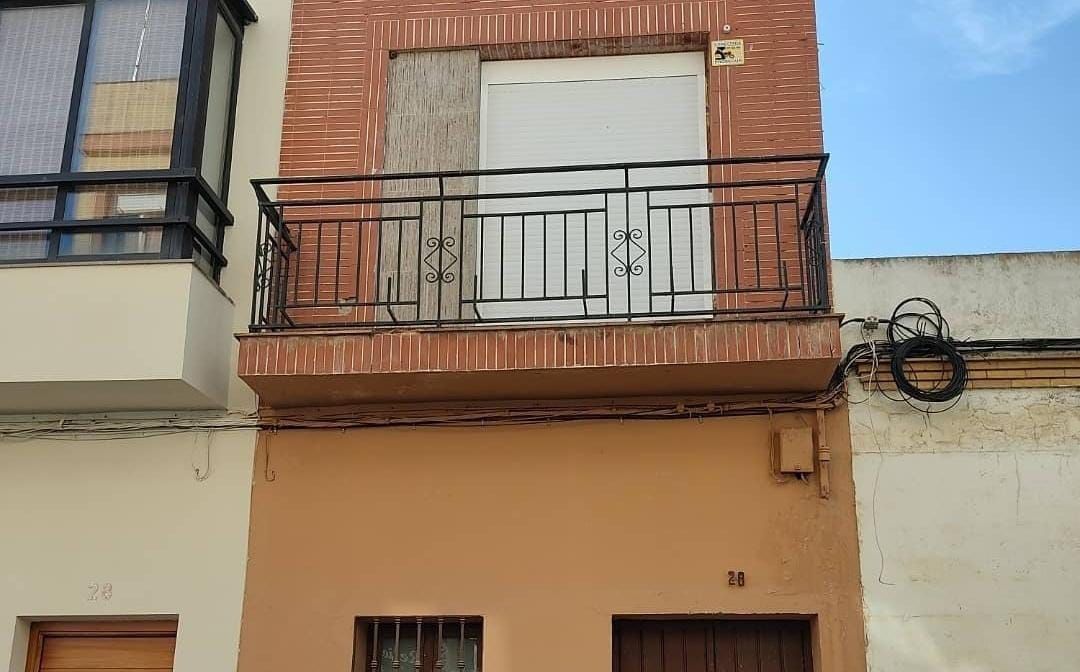 Edificio de dos plantas con detalles de ladrillo y balcón con barandilla negra.