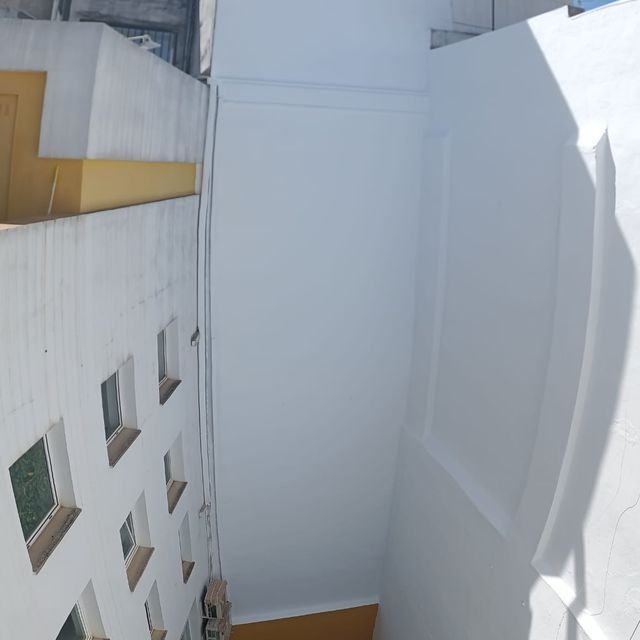 Vista exterior de edificios blancos con pequeñas ventanas cuadradas y un pasillo estrecho.