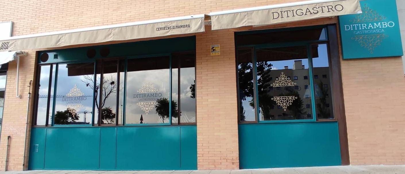 Fachada con detalles en color verde azulado, toldo y un letrero que dice