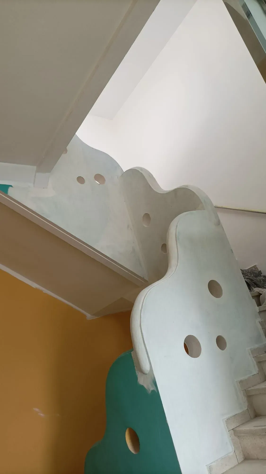 Escalera blanca con diseños calados y paredes de colores.