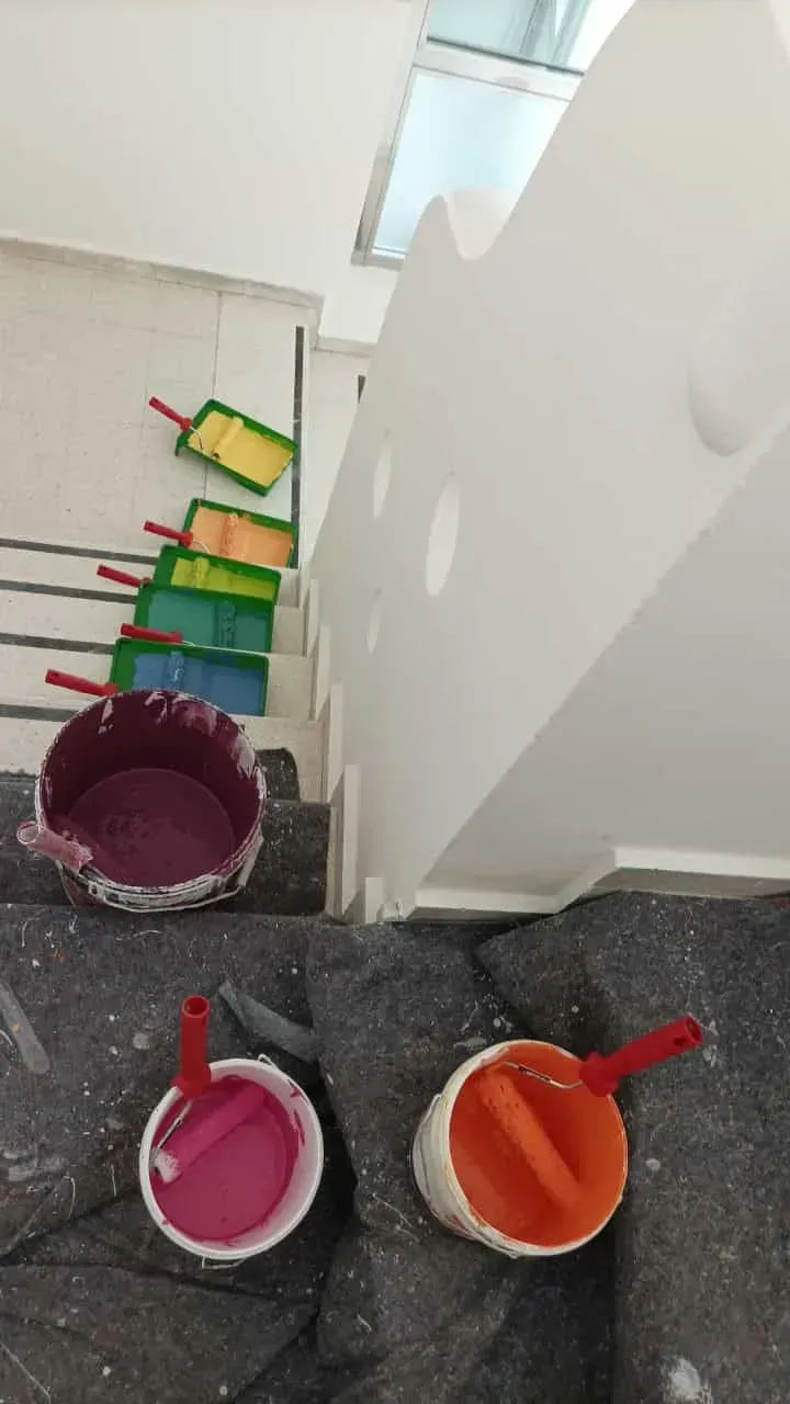 Cubos de pintura, rodillos de pintura y escaleras, vista interior. Suministros de pintura de varios colores se encuentran sobre las escaleras.