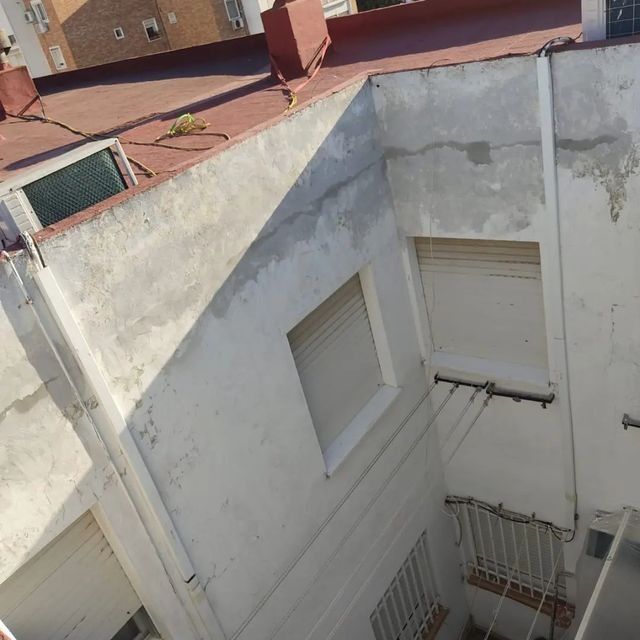 Exterior de un edificio con paredes blancas, ventanas y tejado rojo.
