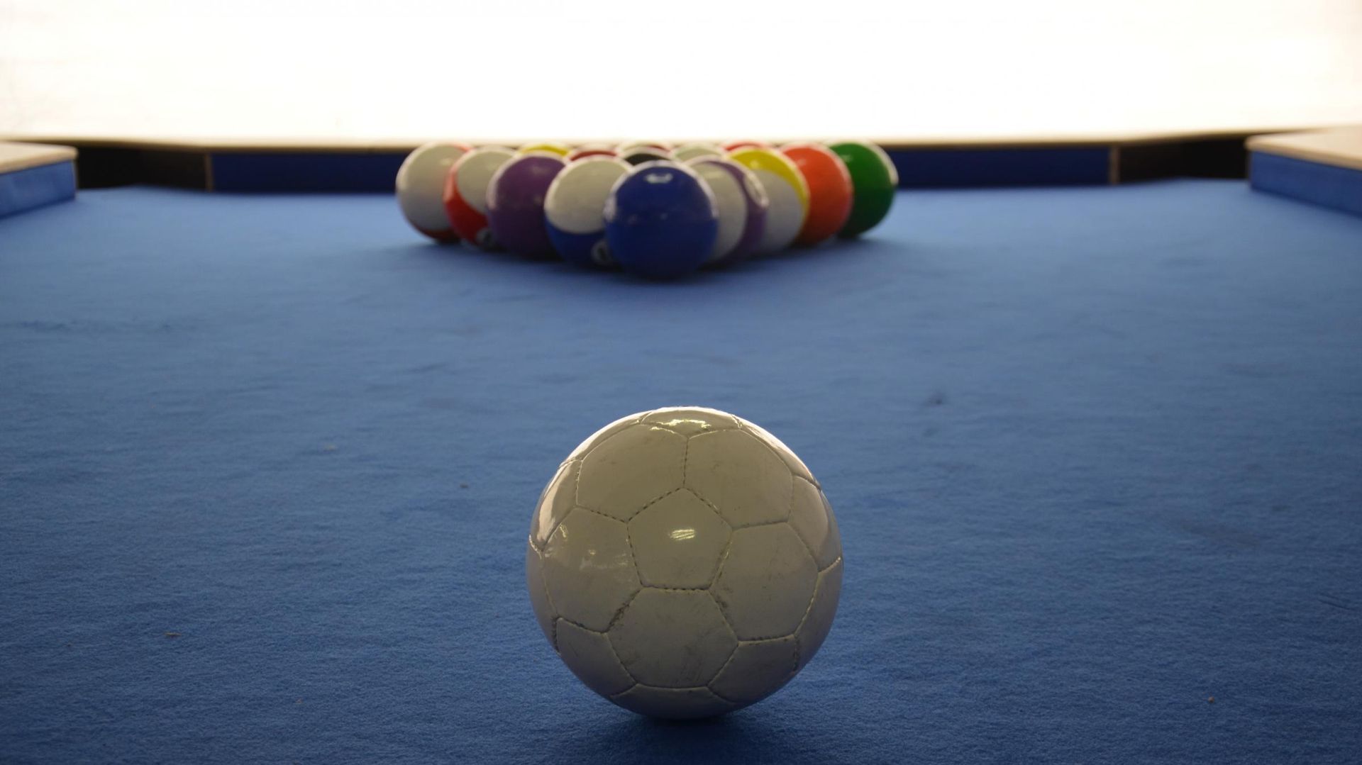 White billiard ball on blue pool table with racked balls in the background