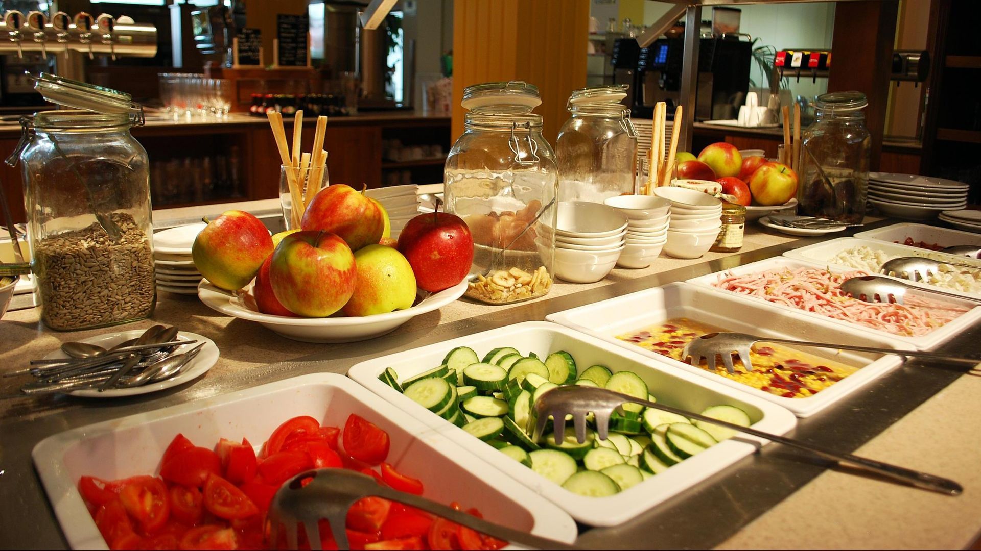 Buffet table with fruit, salads, and desserts in a warm restaurant setting