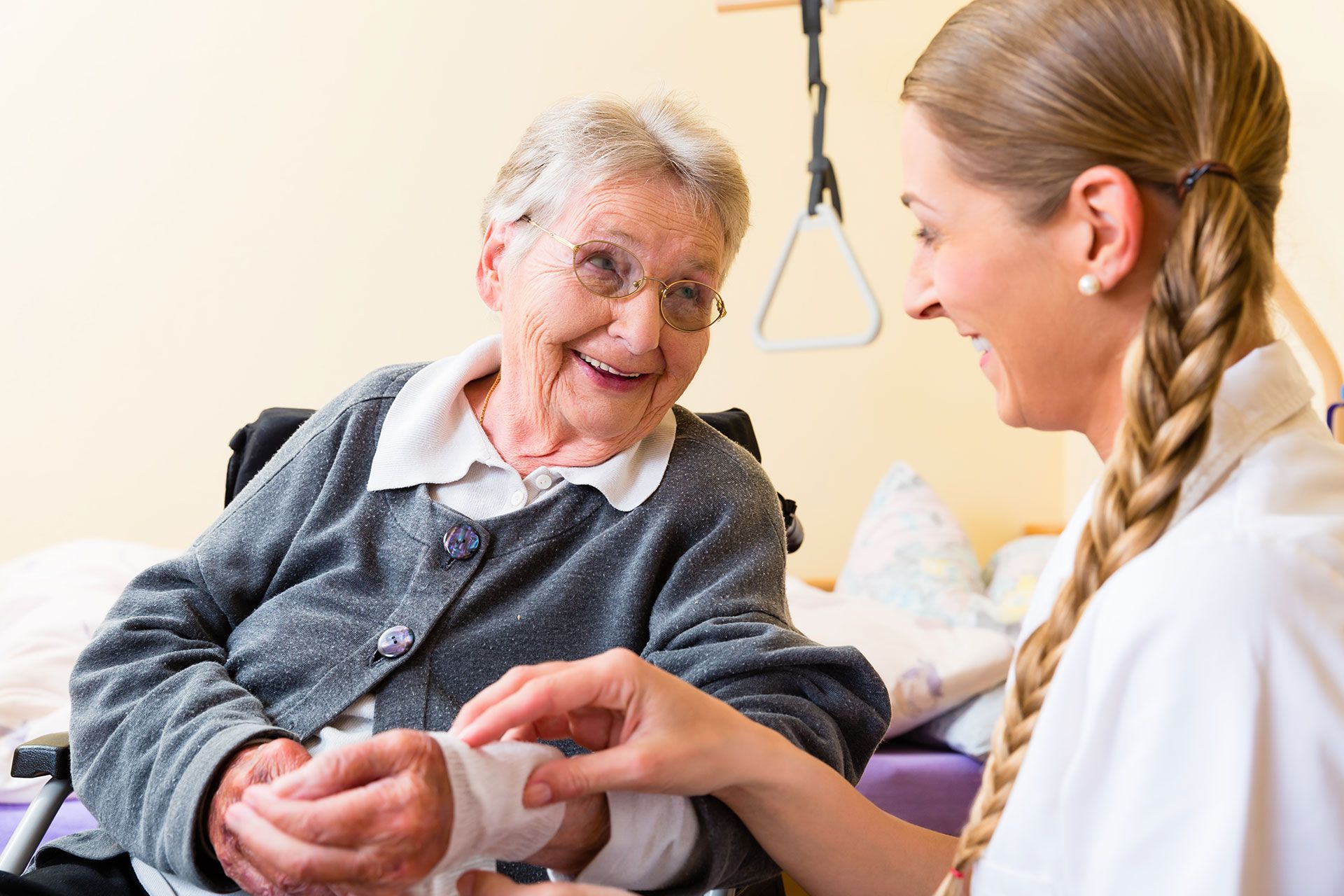 Eine ältere Frau im Rollstuhl wird von einer Krankenschwester versorgt.