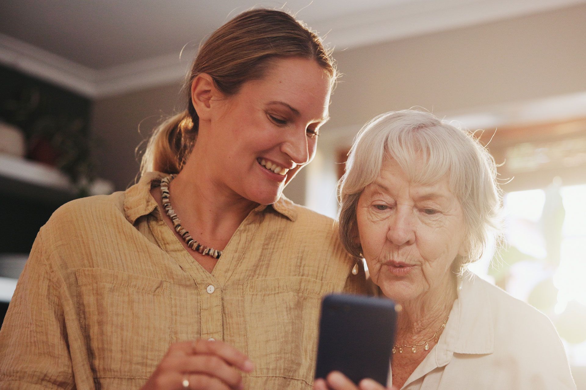 Zwei Frauen schauen gemeinsam auf ein Mobiltelefon.