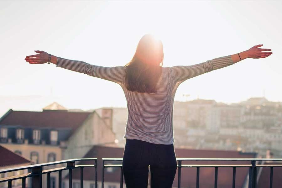 Una mujer está parada en un balcón con los brazos extendidos.