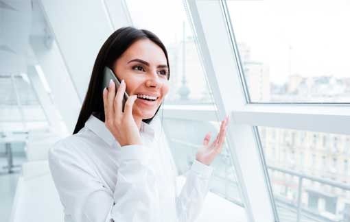 Una mujer habla por un teléfono celular mientras mira por una ventana.