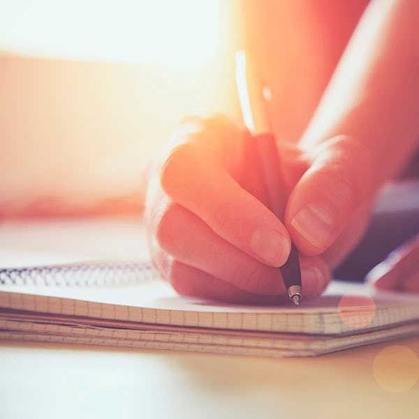 Una persona está escribiendo en un cuaderno con un bolígrafo.