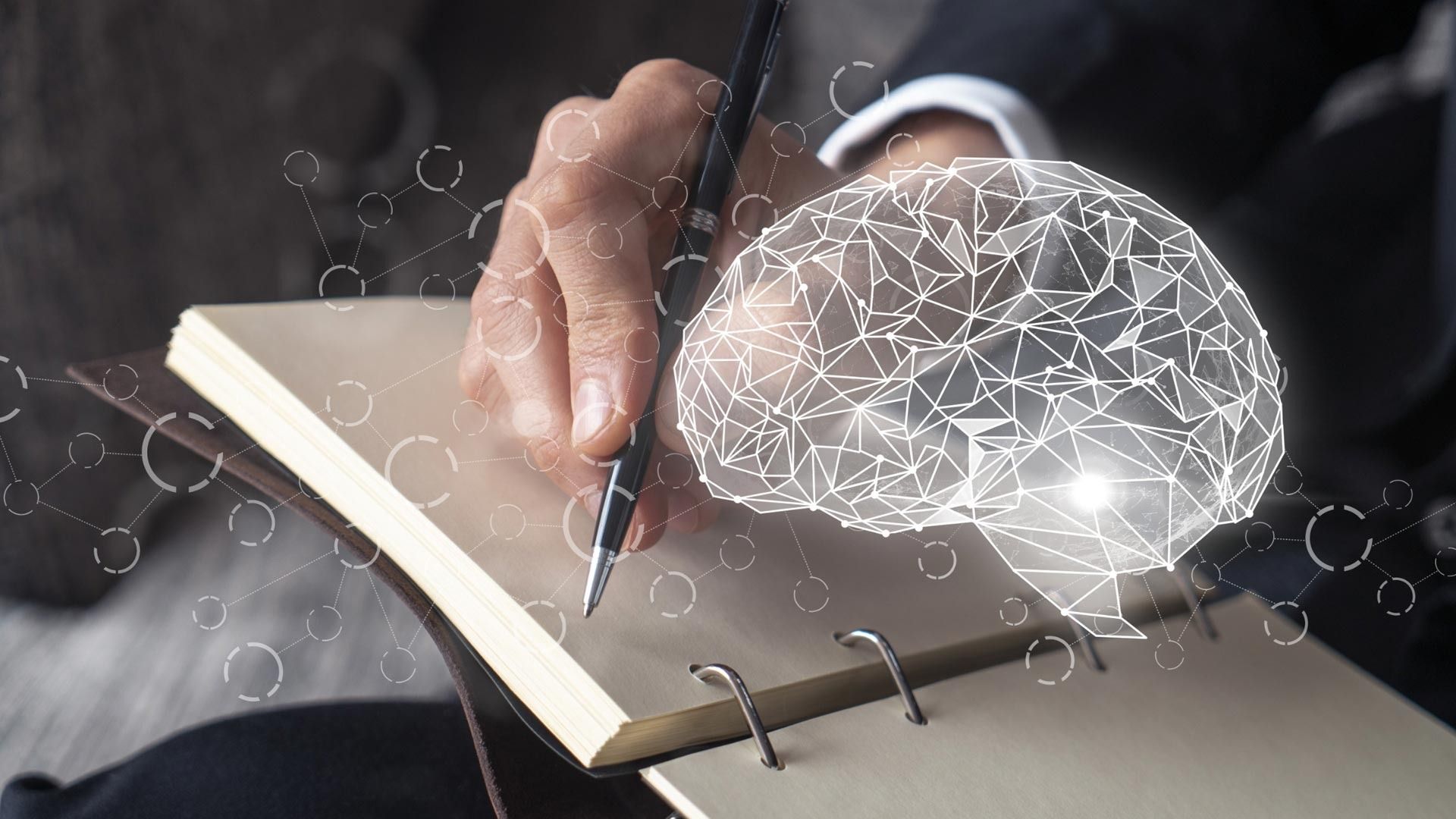 Una persona está escribiendo en un cuaderno con un bolígrafo y de él sale un cerebro.