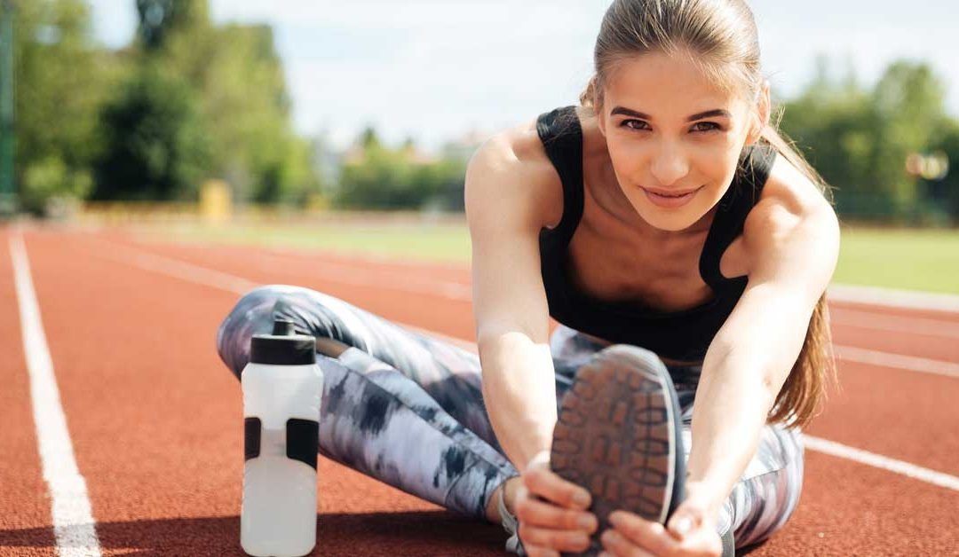 Una mujer está sentada en una pista estirando las piernas.