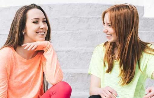 Dos mujeres están sentadas en un tramo de escaleras hablando entre sí.