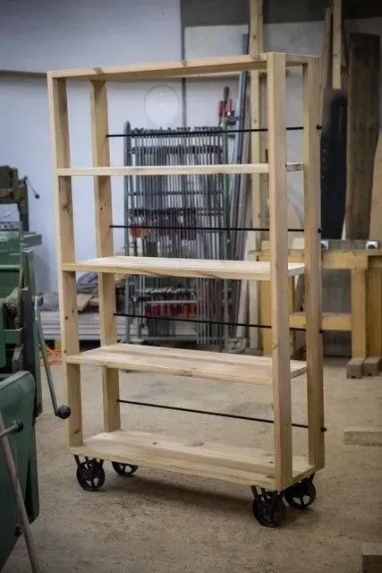 Une étagère en bois avec des roulettes se trouve dans un atelier.