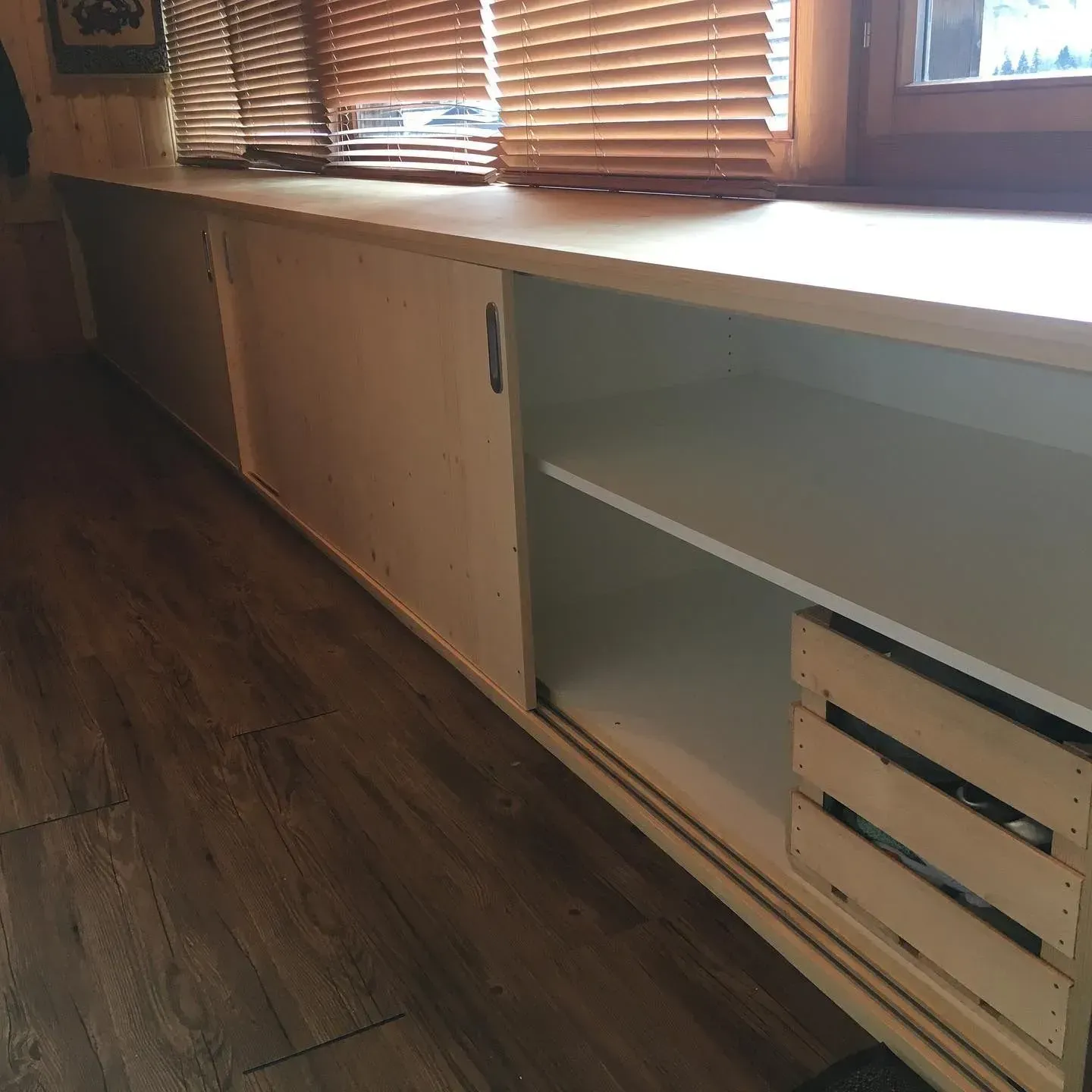 Une fenêtre avec des stores se trouve derrière une armoire blanche