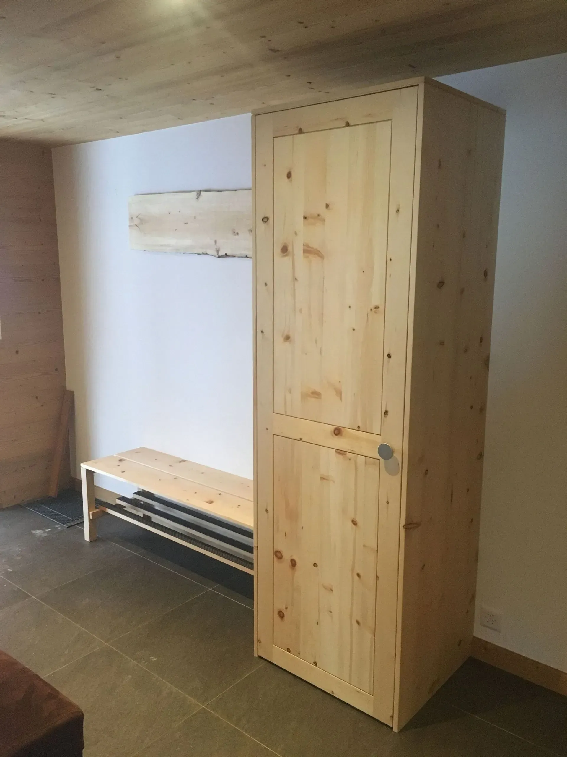 Une armoire en bois se trouve dans une pièce à côté d'un banc
