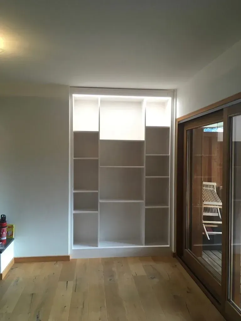 Une pièce avec beaucoup d'étagères et une porte coulissante en verre.