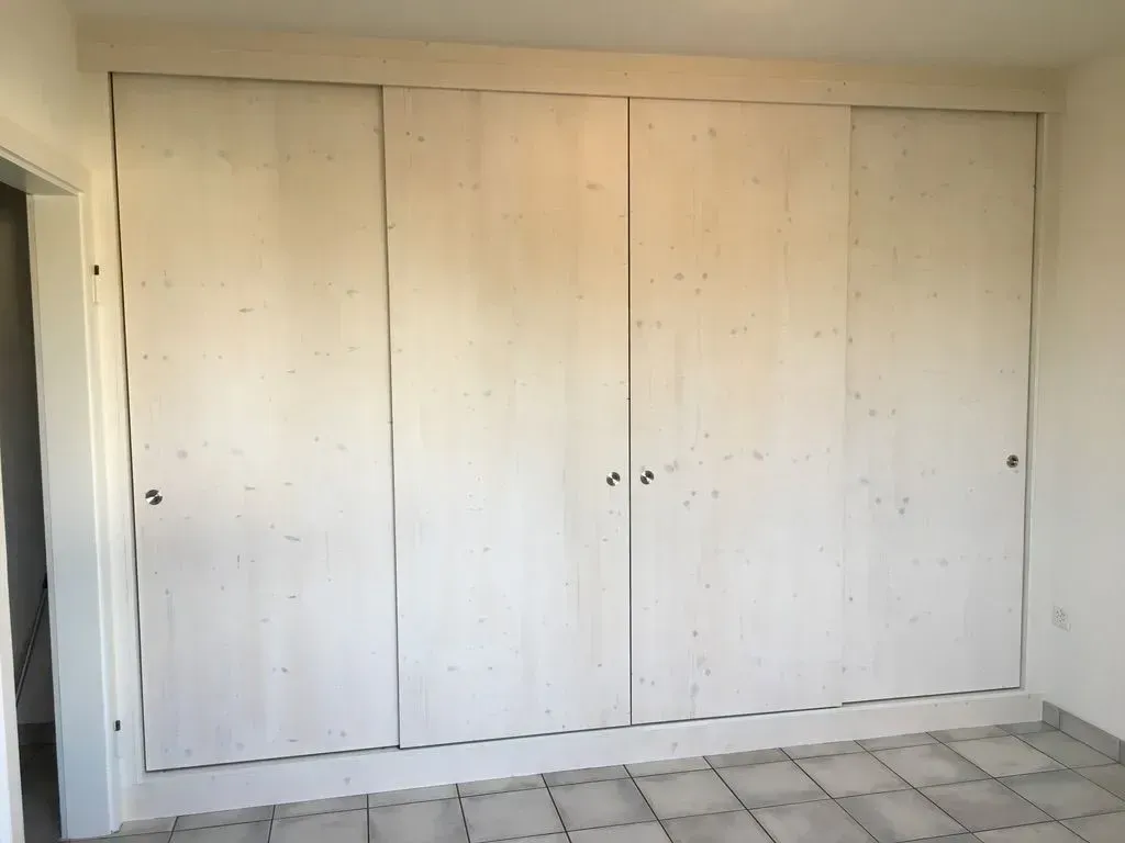 Une pièce avec beaucoup d'armoires blanches et un sol carrelé.