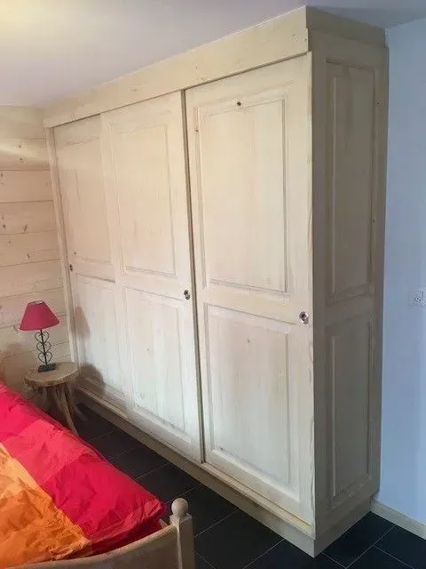 Une chambre avec un lit et une grande armoire en bois.