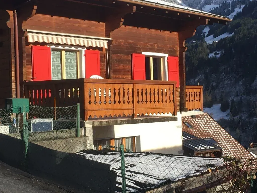 Une maison en bois avec des volets rouges et un balcon