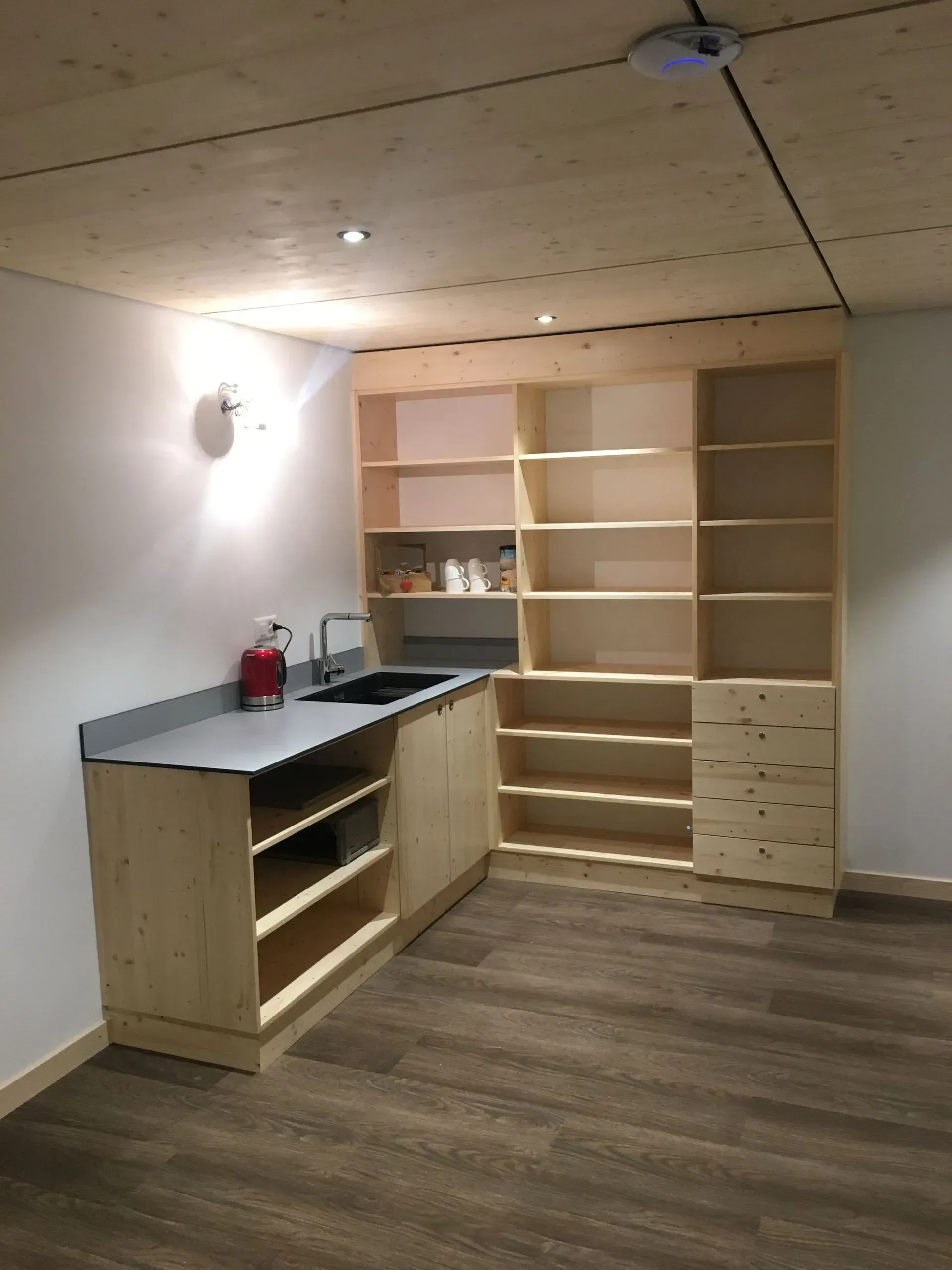 Une cuisine avec des armoires et des étagères en bois et un évier.