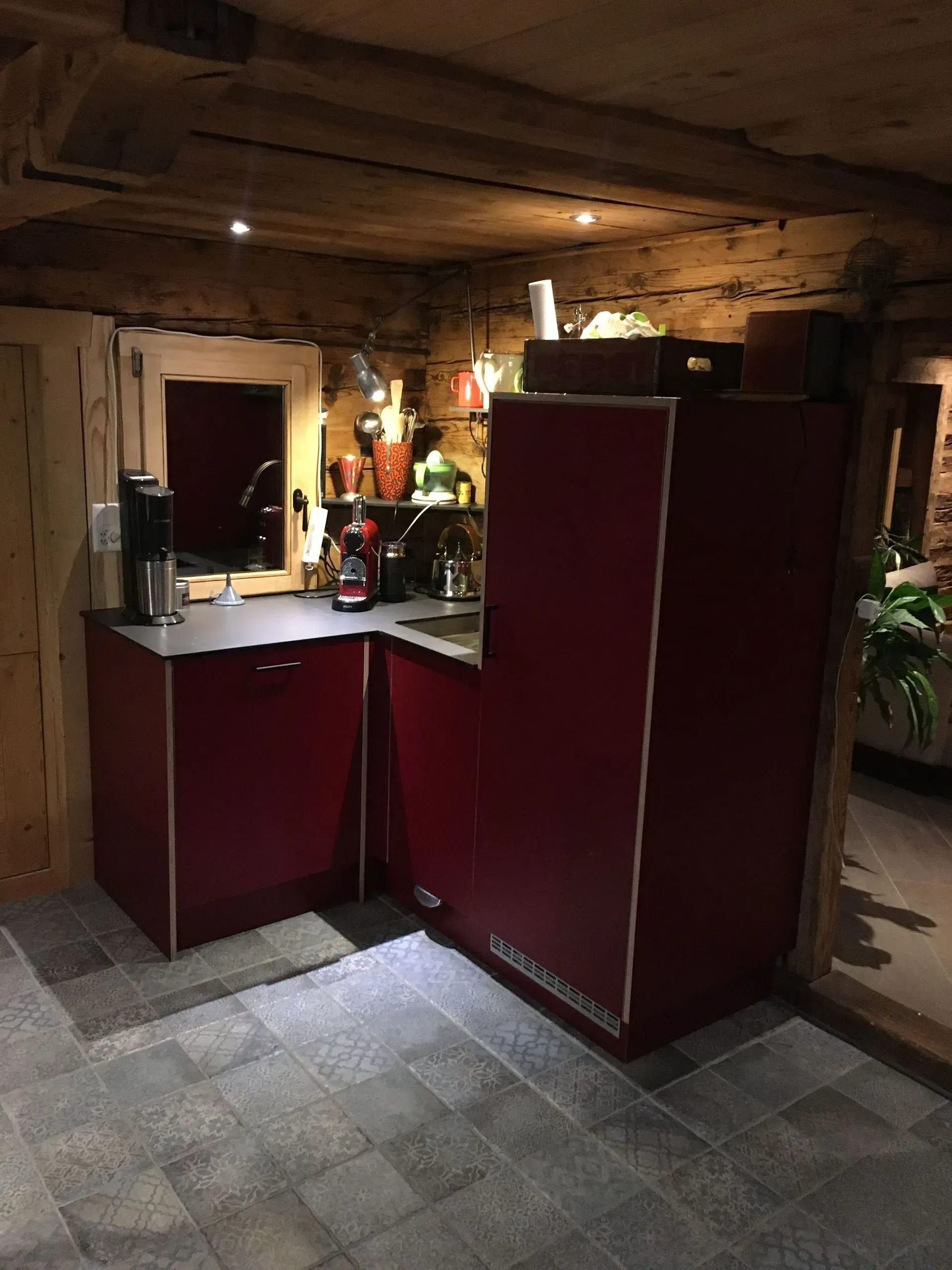 Une cuisine avec des armoires rouges et un sol en carrelage gris