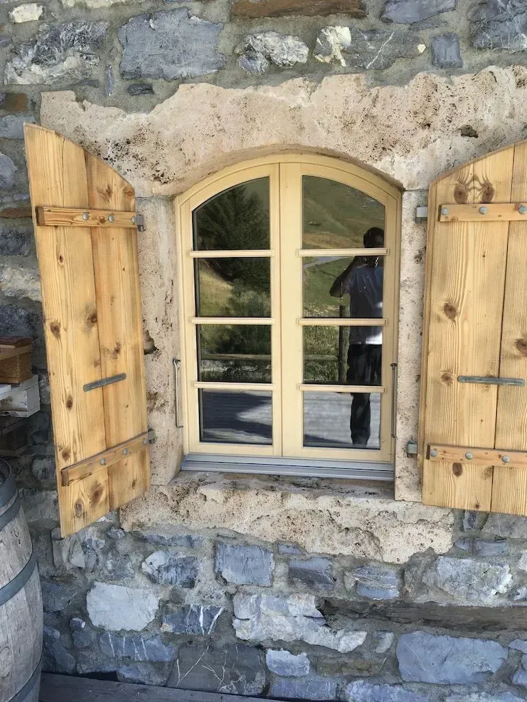 Une fenêtre avec des volets en bois sur un mur de pierre.