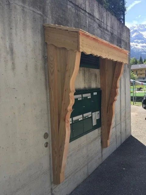 Un mur en béton avec un auvent en bois au-dessus d'une boîte aux lettres