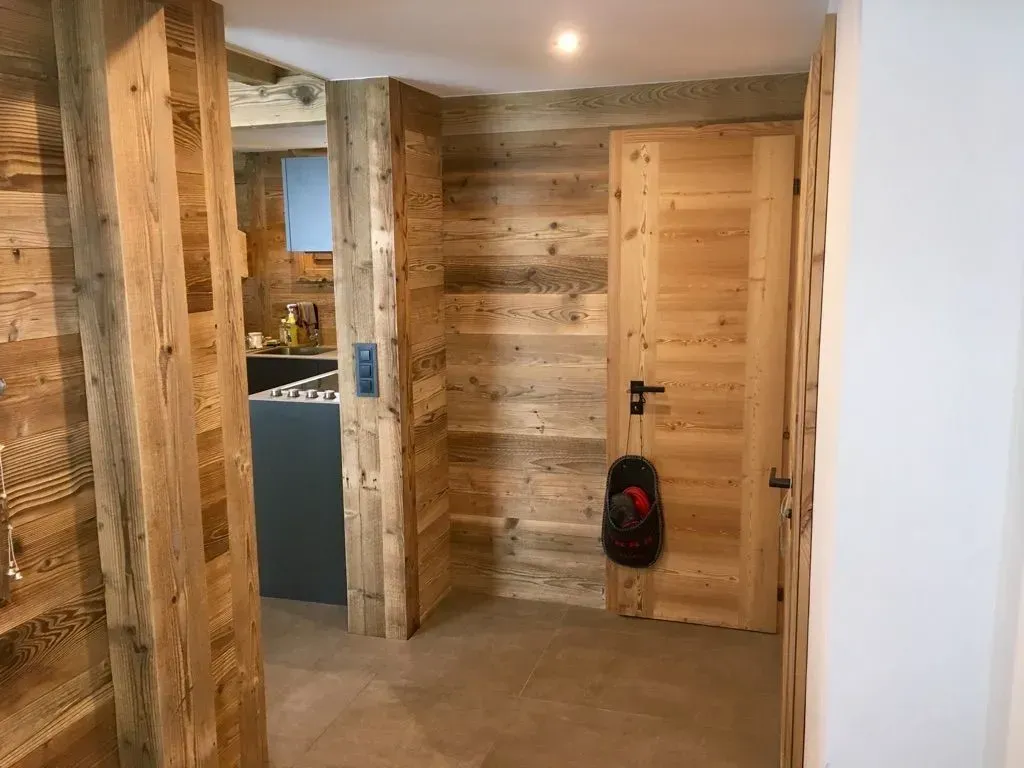 Un couloir avec des murs en bois et un sac à dos accroché à la porte.