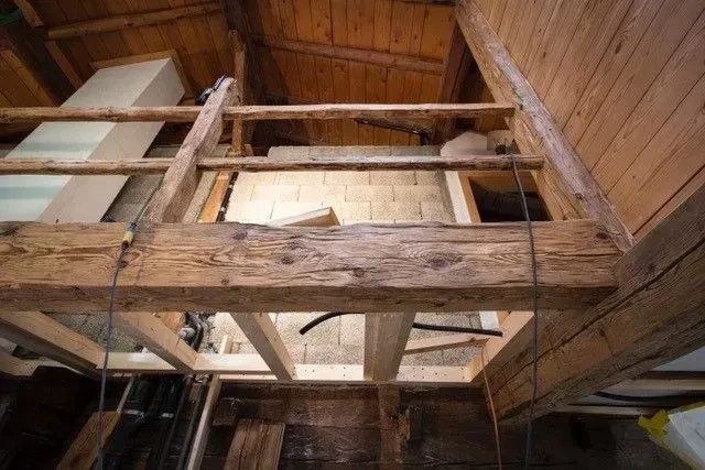 Une structure en bois est en cours de construction dans un grenier.