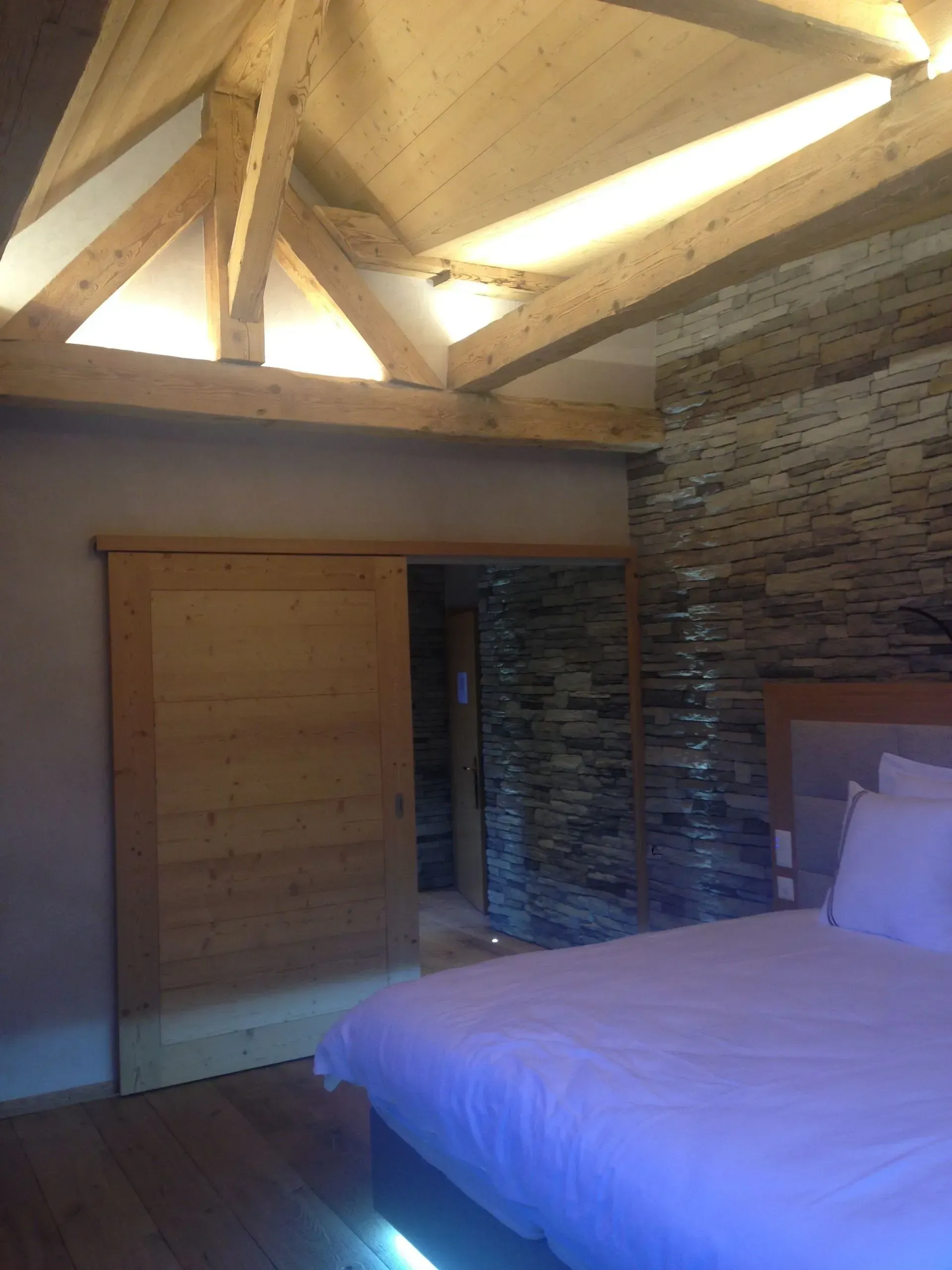 Une chambre avec un lit et un mur en pierre