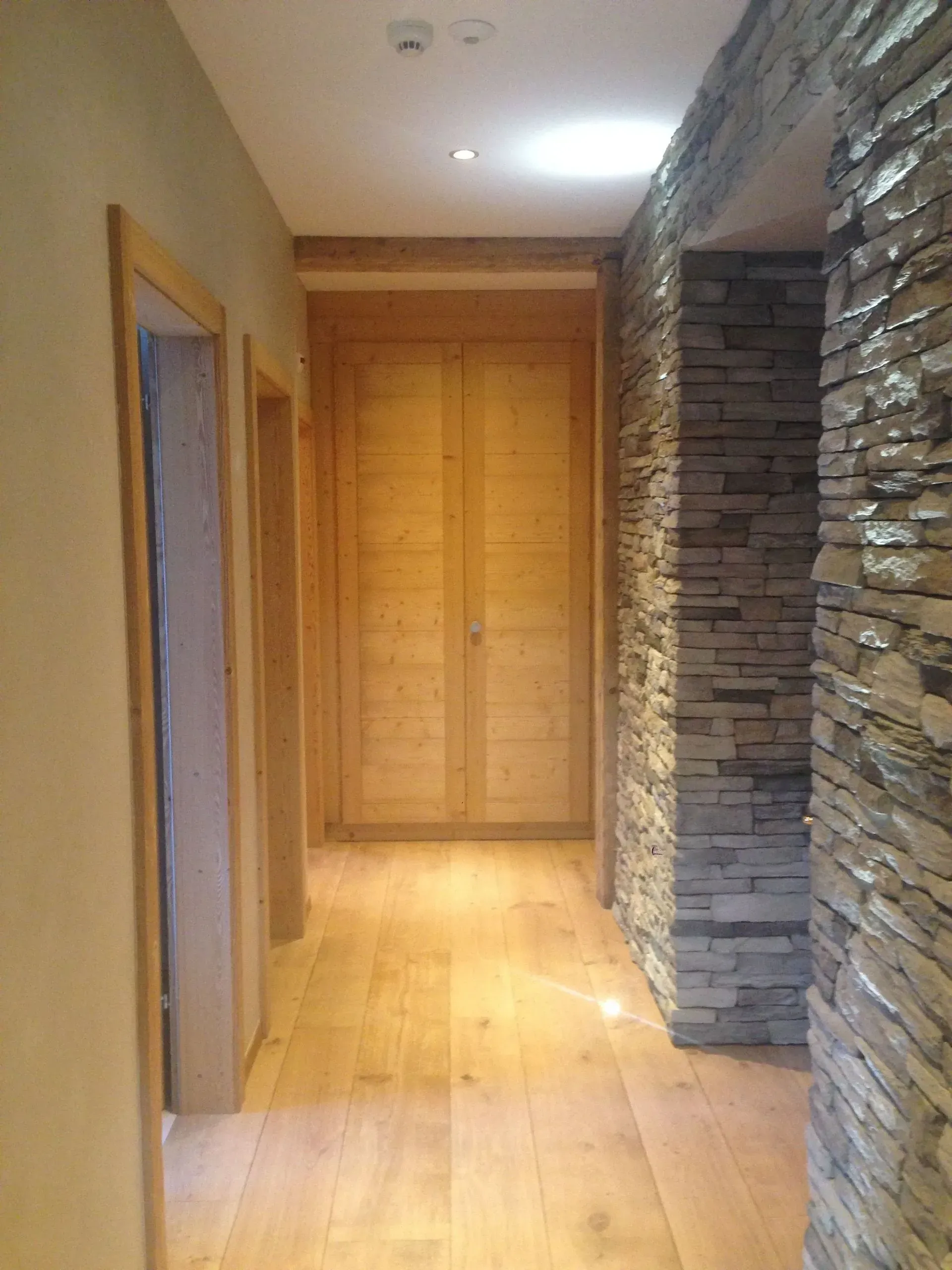 Un couloir avec du parquet et un mur en pierre
