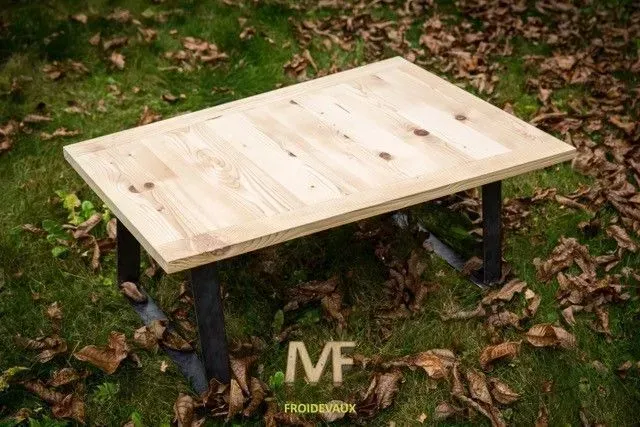 Une table en bois est posée au sommet d'un champ vert luxuriant.