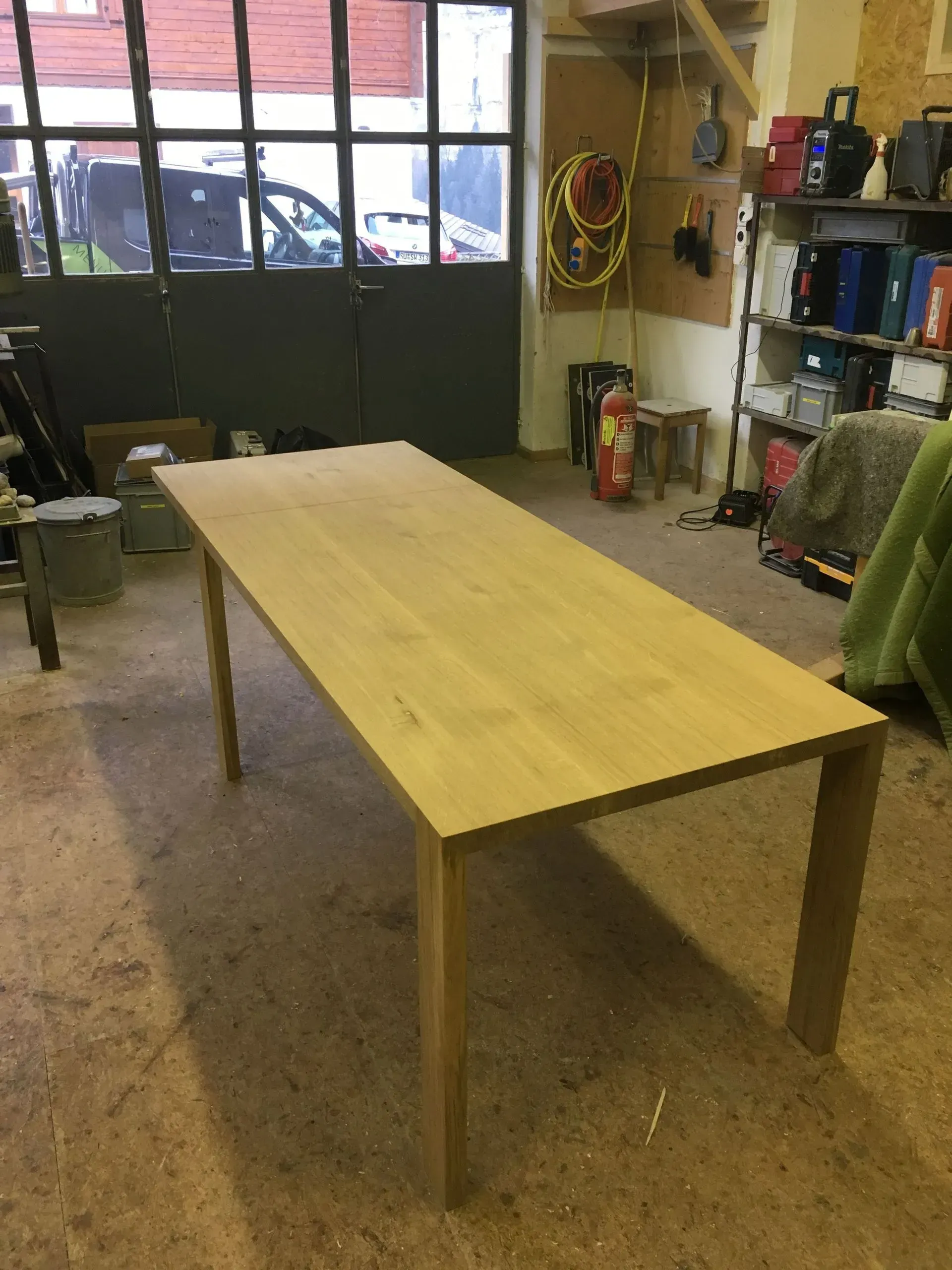 Une table en bois est posée dans un garage à côté d'un extincteur.
