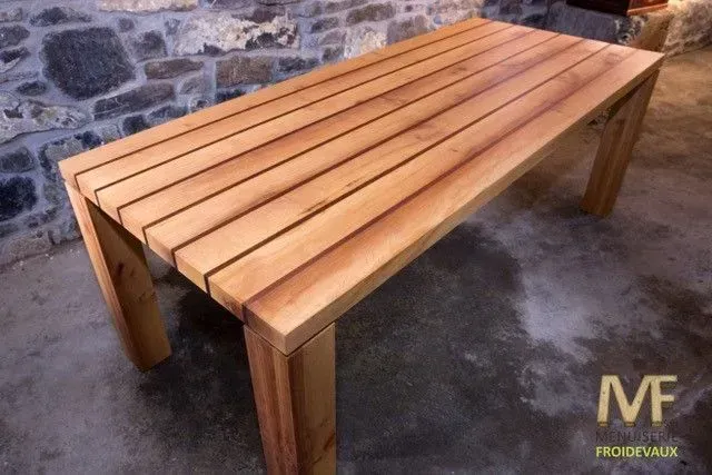 Une table en bois est posée devant un mur de pierre.