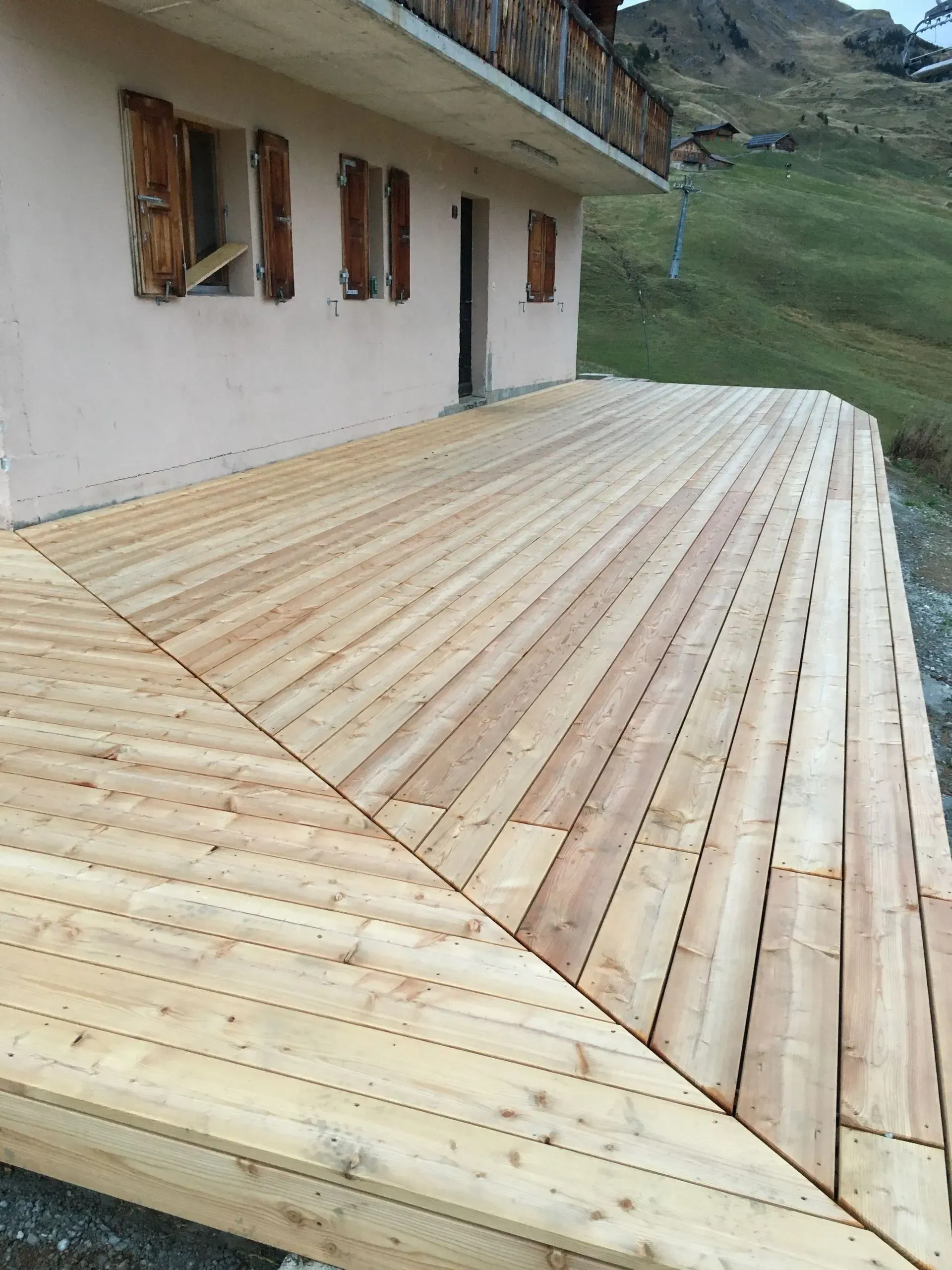 Une grande terrasse en bois se trouve devant une maison.