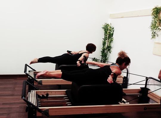 Tres mujeres están haciendo pilates en una máquina de pilates.