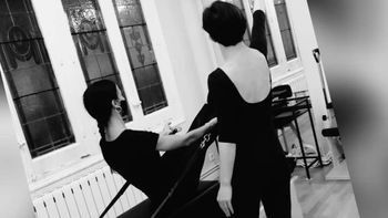 Una fotografía en blanco y negro de dos mujeres paradas una al lado de la otra en una habitación.