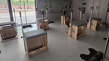 Estudio de ejercicios con varias máquinas de Pilates reformer y ventanales que van del suelo al techo.