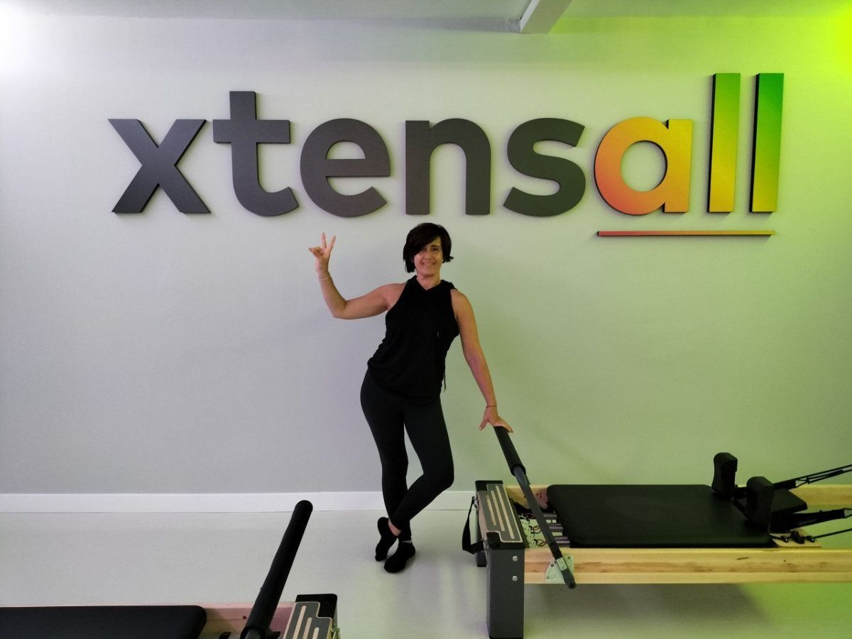 Una mujer está parada frente a un cartel que dice xtensall