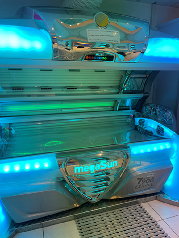 Ein Solarium mit der Aufschrift „megaSun“, das mit orangefarbenen und grünen Lichtern beleuchtet ist.