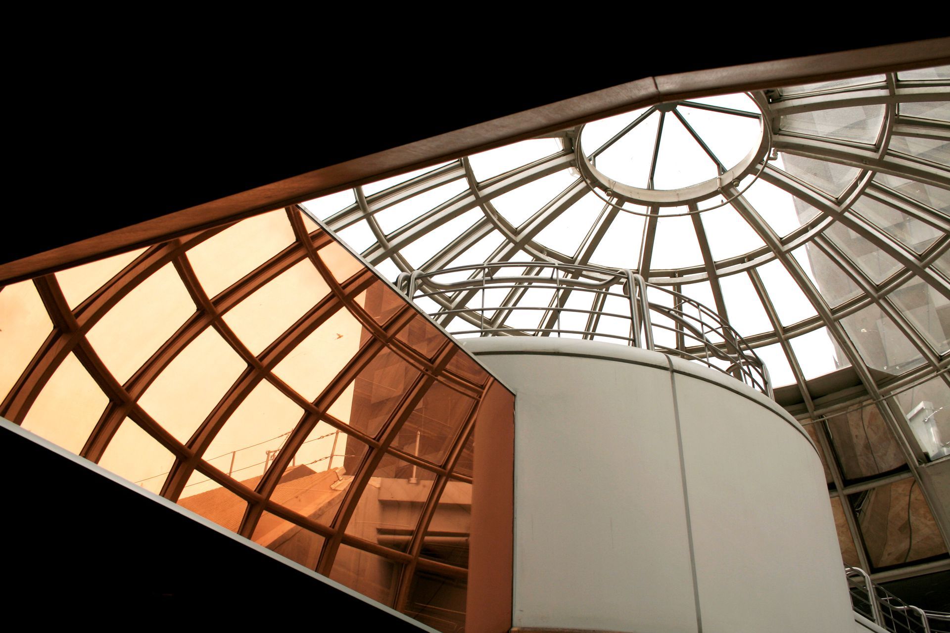 Plafond d'atrium en verre incurvé avec une verrière centrale et des panneaux teintés orange