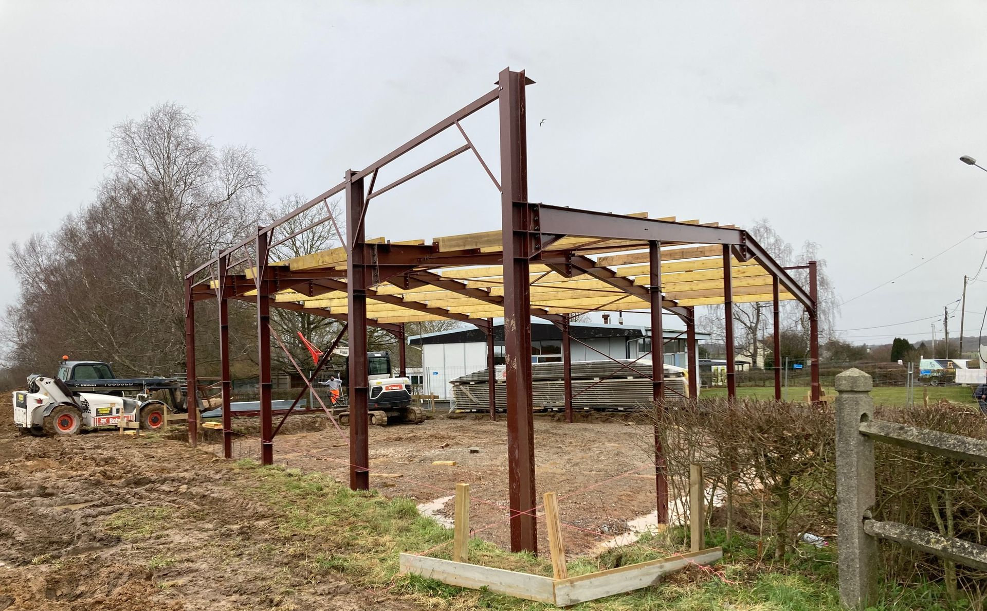 À l'intérieur d'un grand entrepôt à ossature métallique en construction, avec des grues, des poutres et des outils éparpillés au sol