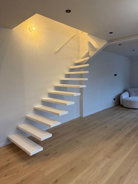 Pièce moderne avec escalier blanc suspendu, parquet clair et canapé beige dans le coin