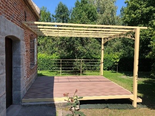 Patio moderne avec pergola, marches, plantes en pot et façade blanche de maison baignée de soleil