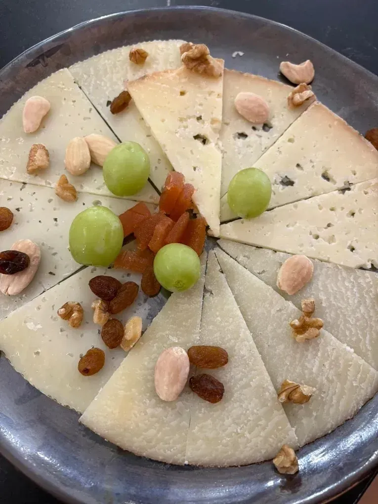 Postre blanco en rebanadas adornado con uvas verdes, pasas y nueces en un plato de metal.
